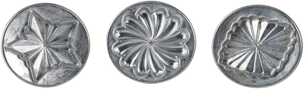 Three vintage, round, metal jelly molds with intricate geometric designs are displayed side by side on a white background—perfect for adding charm to your next flower cookies recipe.